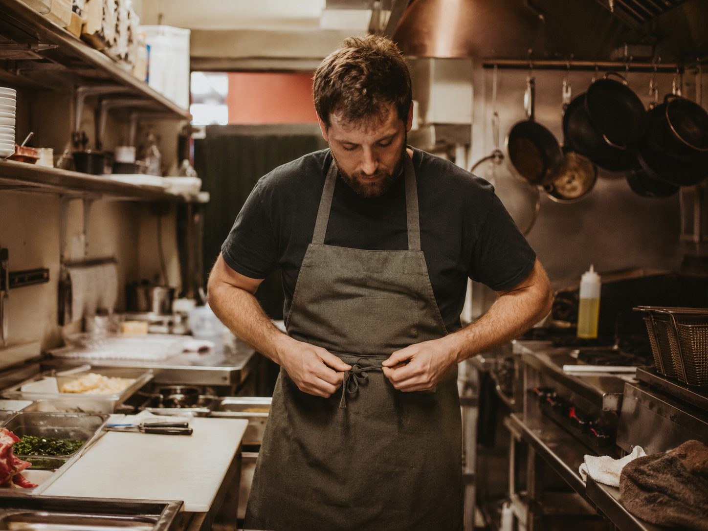 A line cook working alone in a restaurant kitchen